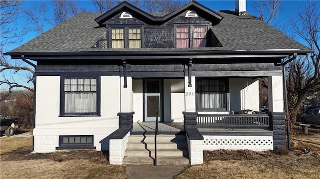 view of front facade featuring a chimney, a porch, and roof with shingles