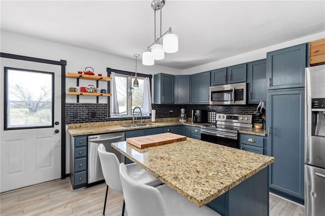 17259 174th St, Basehor, KS 66007 - kitchen with appliances with stainless steel finishes, a sink, light stone counters, a kitchen island, and decorative backsplash