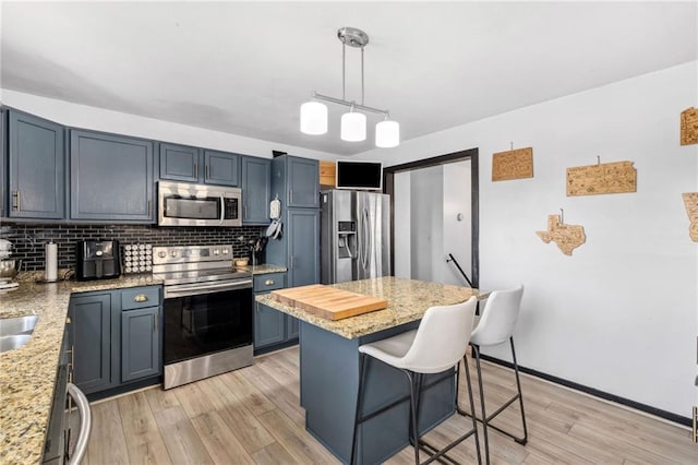 17259 174th St, Basehor, KS 66007 - kitchen featuring stainless steel appliances, decorative backsplash, a kitchen breakfast bar, and light wood-type flooring