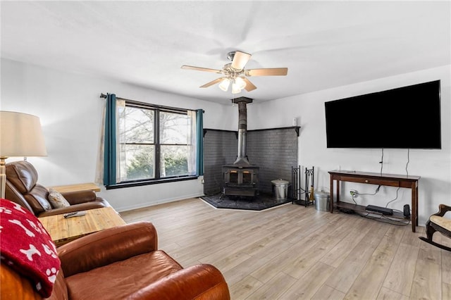 17259 174th St, Basehor, KS 66007 - living room featuring a wood stove, ceiling fan, wood finished floors, and baseboards