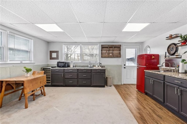 17259 174th St, Basehor, KS 66007 - kitchen featuring a sink, black microwave, a drop ceiling, light wood-type flooring, and light stone countertops
