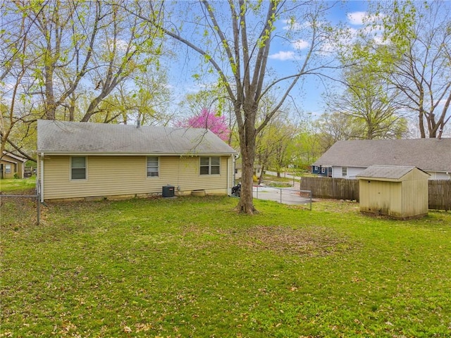 view of yard featuring central AC unit, a storage unit, an outbuilding, and fence
