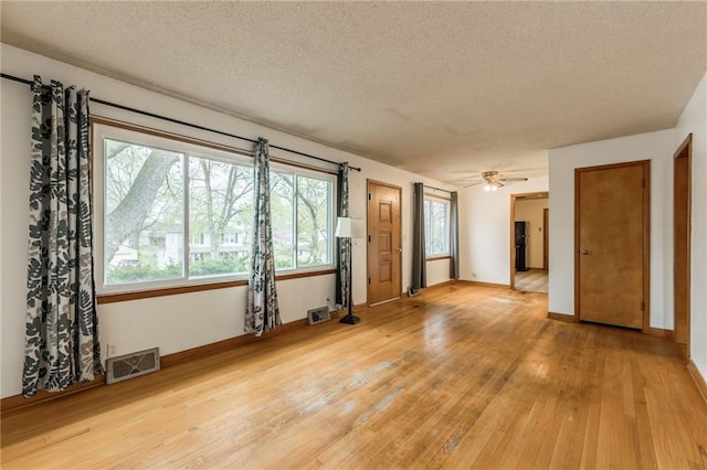 unfurnished room with a textured ceiling, visible vents, and hardwood / wood-style flooring