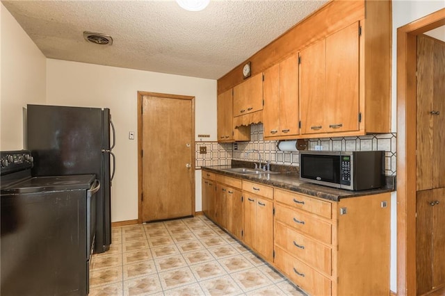 kitchen featuring black range with electric stovetop, stainless steel microwave, dark countertops, tasteful backsplash, and a sink