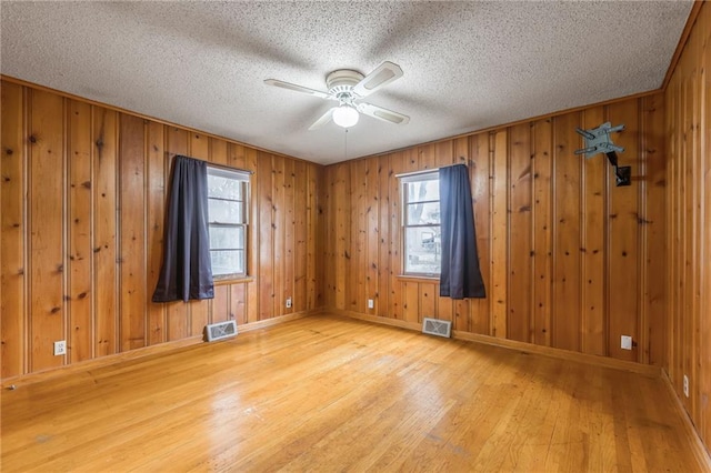 spare room with hardwood / wood-style flooring, visible vents, and plenty of natural light