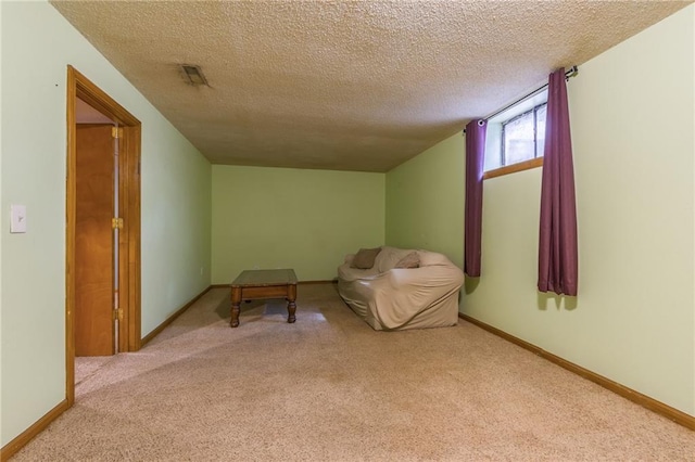 living area with carpet floors, a textured ceiling, baseboards, and visible vents