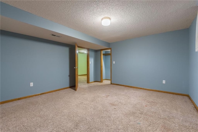 spare room with baseboards, carpet flooring, a textured ceiling, and visible vents
