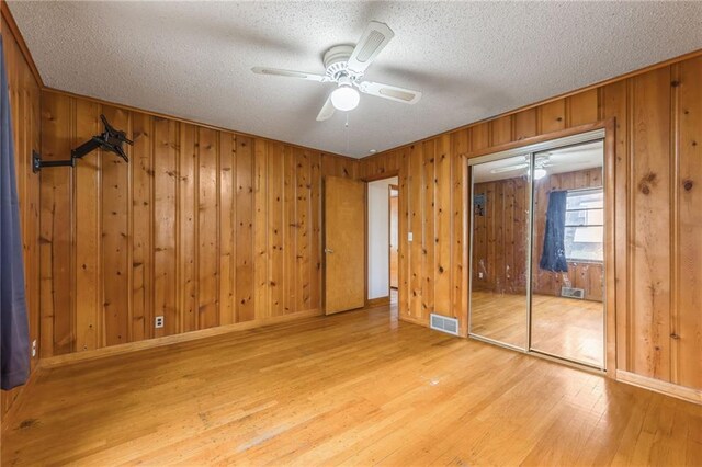 unfurnished bedroom with a textured ceiling, visible vents, baseboards, and hardwood / wood-style floors