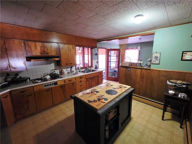 kitchen featuring light floors, cooktop, light countertops, wainscoting, and a sink