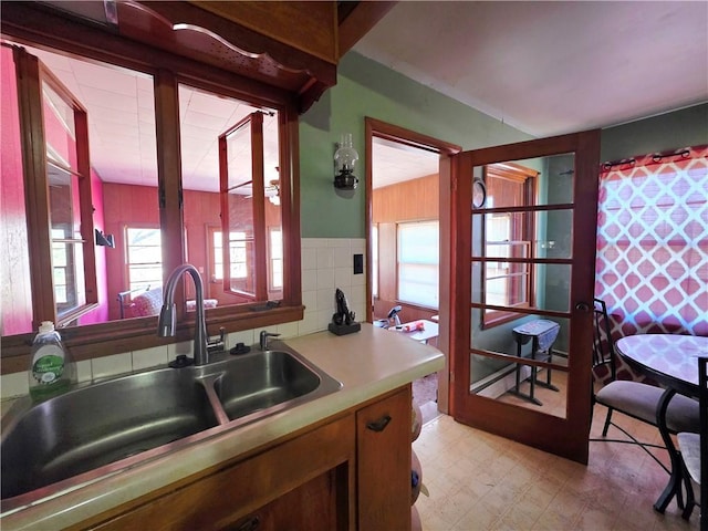 kitchen featuring light countertops, a sink, tile walls, and light floors