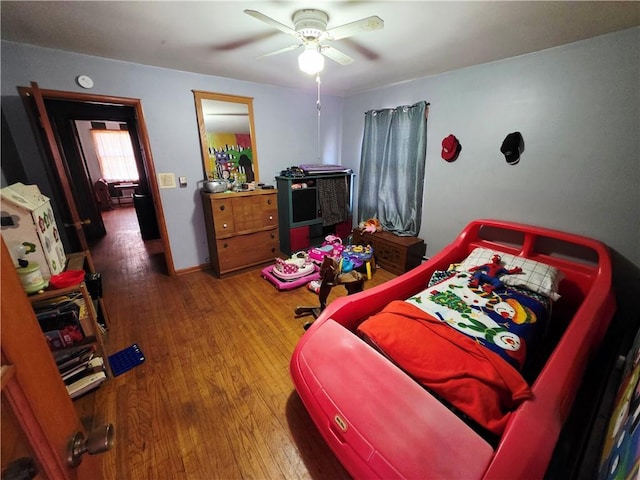 bedroom with ceiling fan, wood finished floors, and baseboards