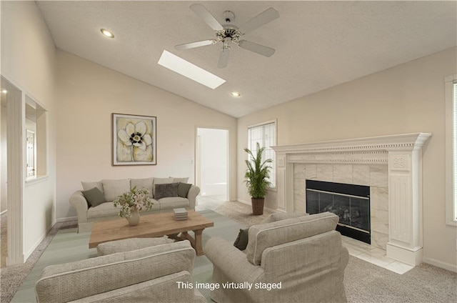 living area featuring carpet floors, lofted ceiling with skylight, a tile fireplace, and recessed lighting