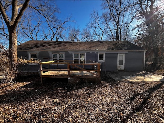 rear view of house featuring a deck, a shingled roof, and a patio area