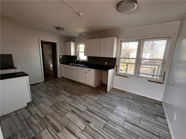 kitchen with a sink, visible vents, white cabinets, tasteful backsplash, and dark countertops