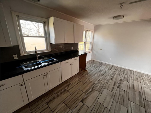 kitchen featuring dark countertops, white cabinets, and a sink