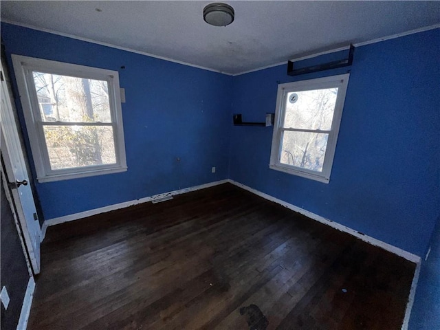 unfurnished room featuring ornamental molding, dark wood finished floors, and baseboards