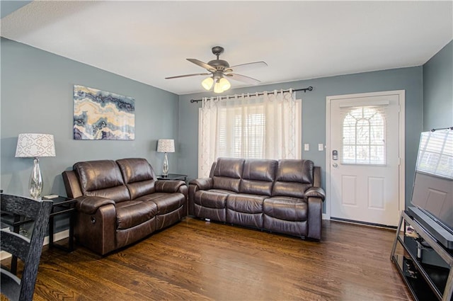 living area featuring a healthy amount of sunlight, a ceiling fan, and dark wood-type flooring