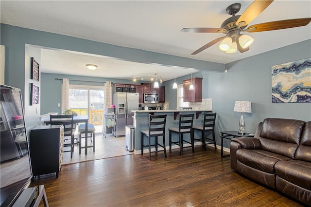 living room featuring dark wood-style flooring, ceiling fan, and baseboards