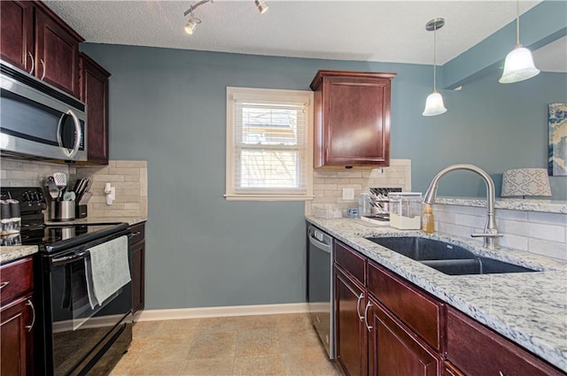 kitchen featuring reddish brown cabinets, baseboards, light stone countertops, stainless steel appliances, and a sink