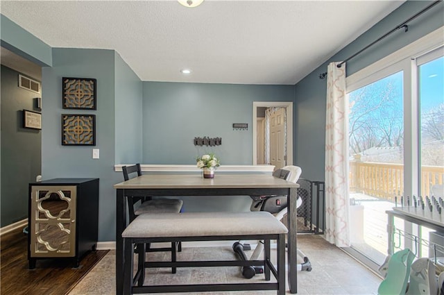 dining area featuring a textured ceiling, visible vents, and baseboards