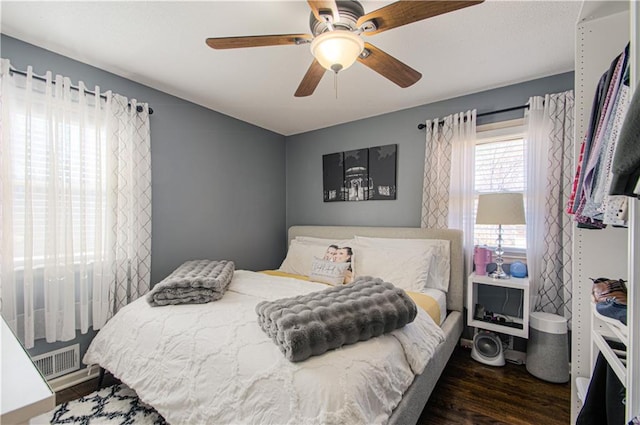 bedroom featuring a ceiling fan, visible vents, and wood finished floors