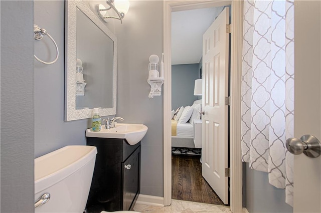 bathroom featuring toilet, ensuite bath, baseboards, and vanity