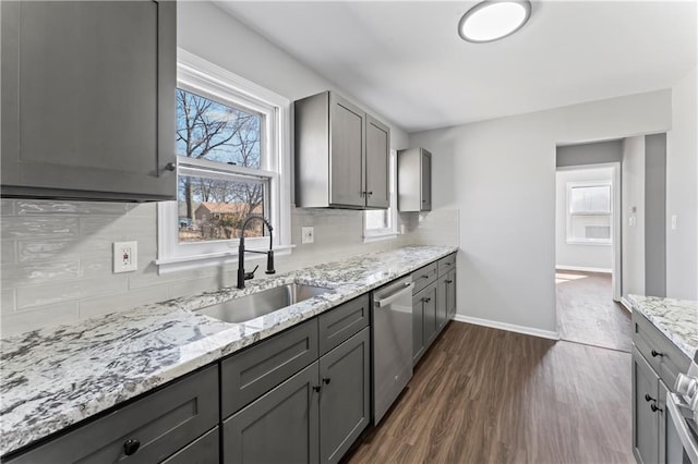 kitchen featuring decorative backsplash, gray cabinets, a sink, and stainless steel dishwasher