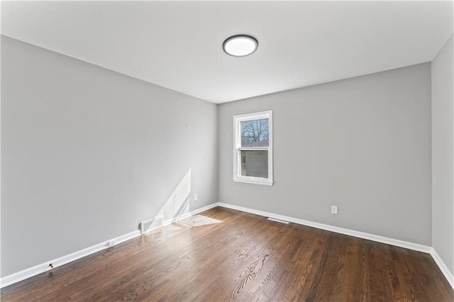 unfurnished room with wood finished floors, visible vents, and baseboards