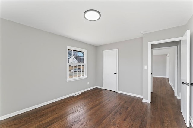 unfurnished bedroom with dark wood-type flooring and baseboards