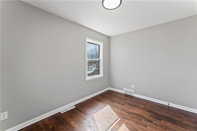 empty room featuring baseboards, visible vents, and wood finished floors