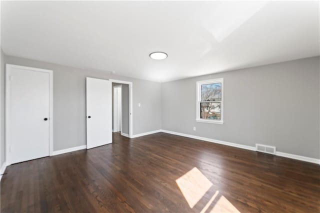 unfurnished bedroom featuring visible vents, baseboards, and wood finished floors