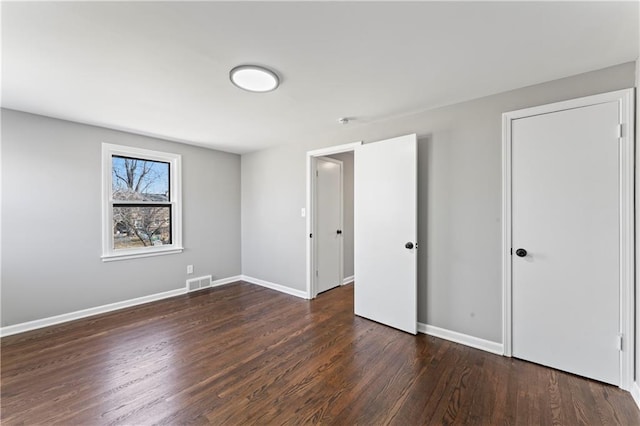 unfurnished bedroom with baseboards, visible vents, and wood finished floors