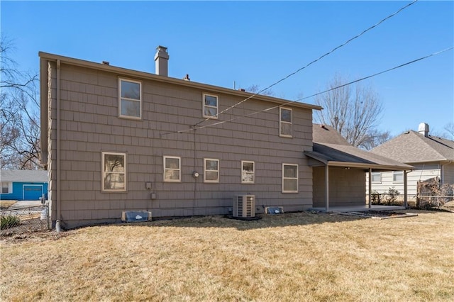 rear view of property with cooling unit, a lawn, a chimney, and fence