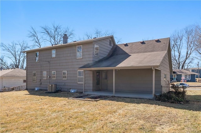 rear view of property with central air condition unit, fence, a lawn, a chimney, and a patio area