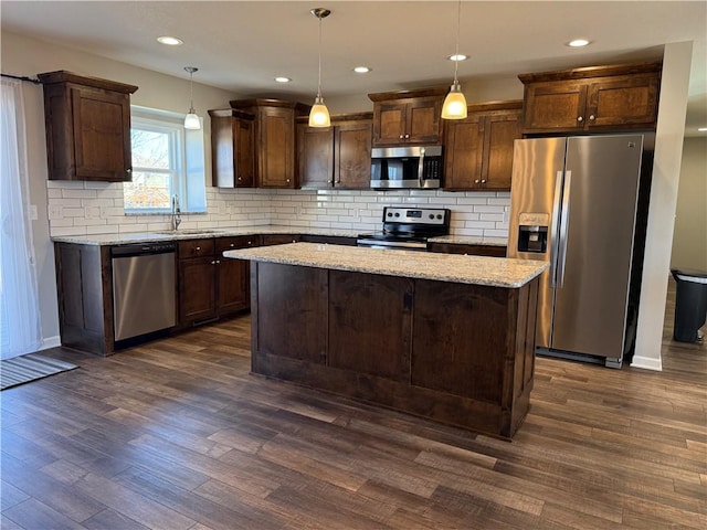 kitchen with dark wood-style floors, a kitchen island, appliances with stainless steel finishes, dark brown cabinets, and a sink