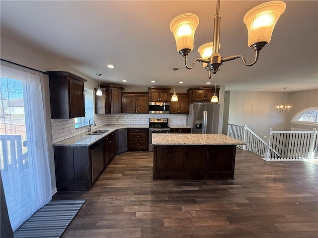 kitchen with stainless steel appliances, a sink, a wealth of natural light, and a notable chandelier