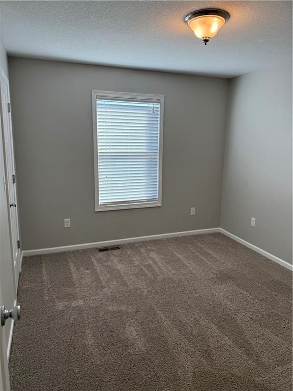 carpeted empty room with a textured ceiling, visible vents, and baseboards