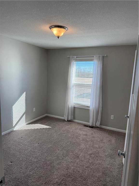 carpeted spare room featuring visible vents, a textured ceiling, and baseboards