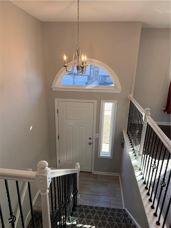 foyer with a towering ceiling, an inviting chandelier, and baseboards