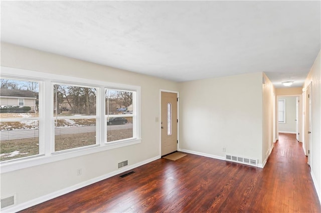 foyer entrance featuring a wealth of natural light, visible vents, and wood finished floors