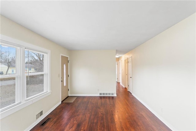 spare room with wood finished floors, visible vents, and baseboards