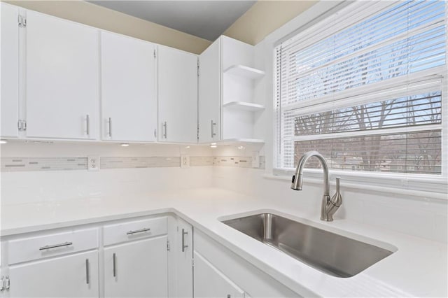 kitchen with light countertops, white cabinets, open shelves, and a sink