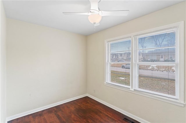 empty room featuring visible vents, a ceiling fan, dark wood-type flooring, and baseboards