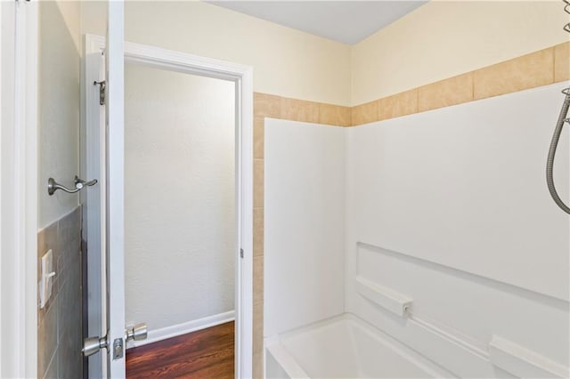 bathroom with baseboards, shower / tub combination, and wood finished floors