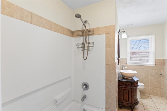 bathroom with tile patterned flooring, toilet, vanity, tile walls, and  shower combination