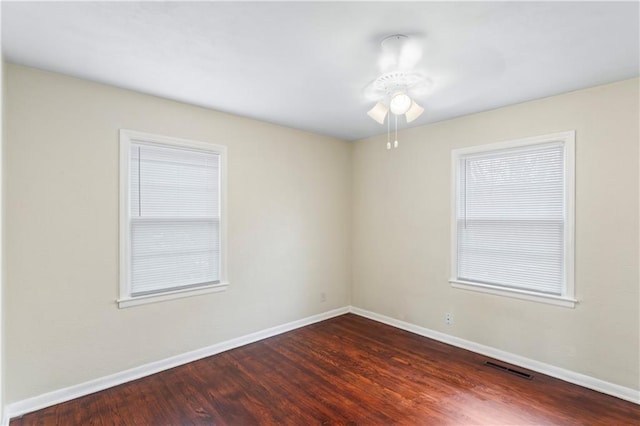 unfurnished room featuring wood finished floors, baseboards, and visible vents