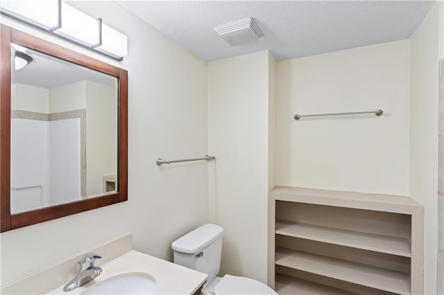 bathroom featuring visible vents, toilet, vanity, and a textured ceiling