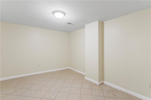 unfurnished room with light tile patterned floors, visible vents, baseboards, and a textured ceiling