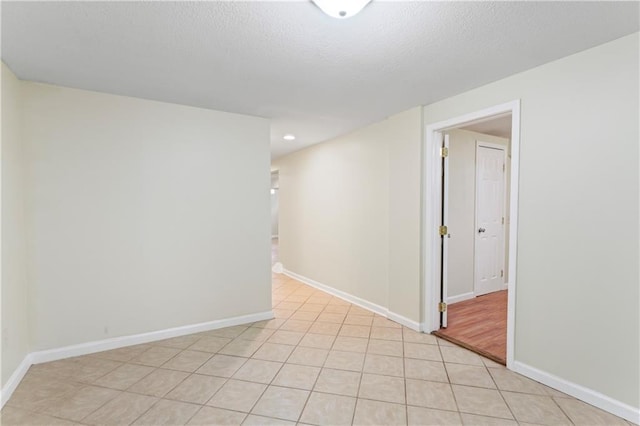 empty room featuring light tile patterned floors, recessed lighting, a textured ceiling, and baseboards