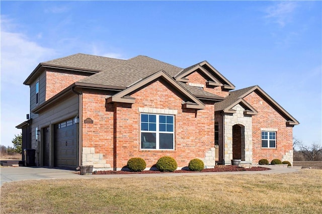 view of front facade with brick siding, concrete driveway, stone siding, roof with shingles, and a front yard